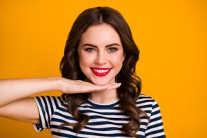 young woman against an orange background showing off her new white smile